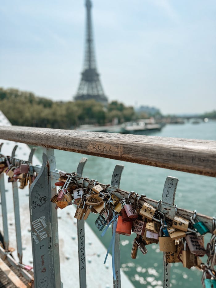 Love locks on a Paris bridge rail with the Eiffel Tower in the background, symbolizing romance.